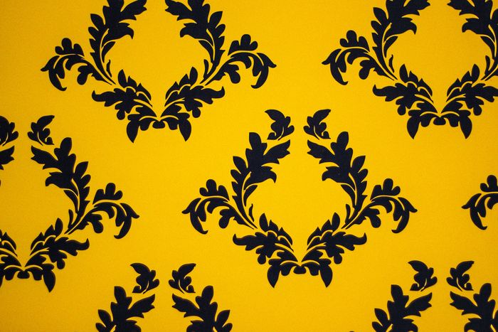 Close-up of black flocked filigree pattern on a saffron yellow wallcovering